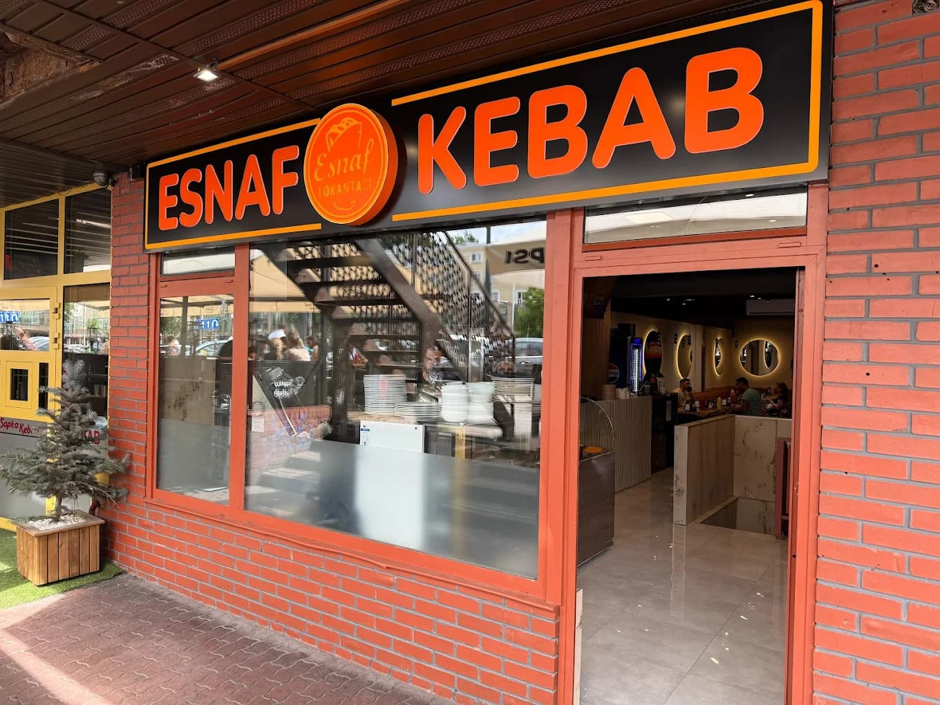 Esnaf Kebab — okrągłe logo restauracji z napisem Esnaf Lokantasi na pomarańczowym tle